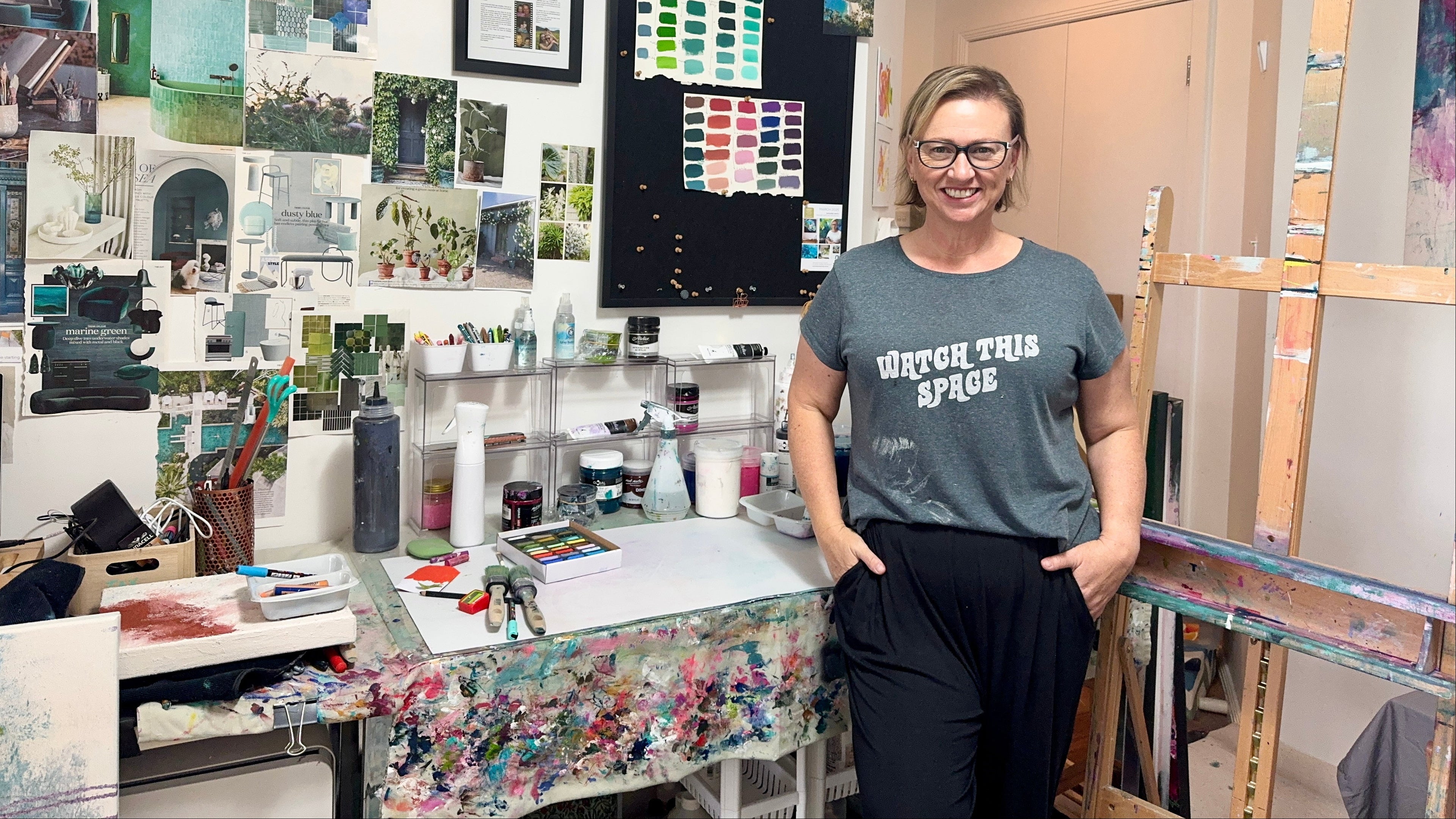Artist Dayarne Smith standing in her art studio with art supplies and a bulletin board.